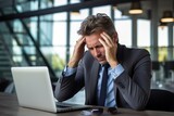 Fototapeta  - Mann mit Kopfschmerzen am Arbeitsplatz im Büro. Überanstrengung und Verzweiflung am Laptop im Business. Verspannungen und schmerzen durch Überarbeitung.