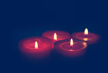Four Burning Red Advent Candles On Black Background.