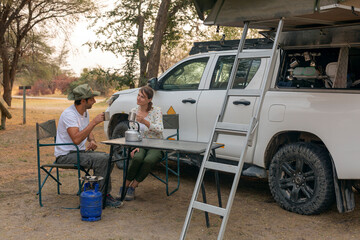 Wall Mural - couple sitting in portable chairs drinking tea talking. camping summer activities