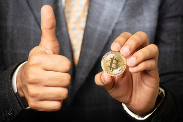 Wall Mural - Hand holding bitcoin and showing thumbs up