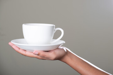 Wall Mural - Cup of tea with saucer in hand on grey background