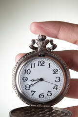 Wall Mural - Closeup of pocket watch in hand on grey background