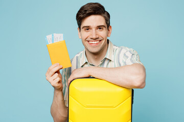 Poster - Traveler smiling fun man wear shirt casual clothes hold bag passport ticket isolated on plain blue background. Tourist travel abroad in free spare time rest getaway. Air flight trip journey concept.