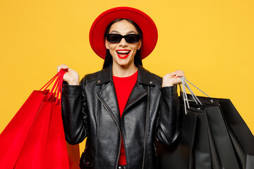 Wall Mural - Young surprised shocked happy satisfied woman wear casual clothes red hat sunglasses hold shopping paper package bags look camera isolated on plain yellow background Black Friday sale buy day concept