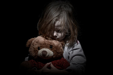 Sad little girl embracing her teddy bear - feels lonely - if you are small girl teddy bear is willing to be your best friend - vintage filter applied