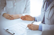 © rogerphoto - Doctor and patient discussing current health questions while sitting near of each other and using clipboard at the table in clinic, just hands closeup. Medicine concept