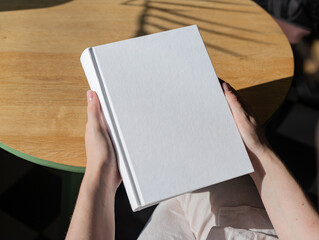 Aufkleber - Book cover mockup, hand holding blank clean hardcover mock up on wood desk