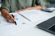 © mojo_cp - Businesswoman reading business document and working about calculating tax with laptop in office.