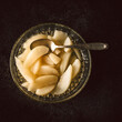 Birnenkompott, Birnen gekocht in einer Glasschüssel, Schale auf dunklem Hintergrund mit Tuch und roher Birne, Kompott, Dessert, Nachtisch. Draufsicht, Vogelperspektive