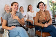 © JackF - Laughing young girl participating in study session, sitting in auditorium with group of women and listening to lecturer..