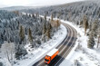 Aerial view of a semi truck moving on the winding winter road with wet surface and snow