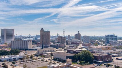 Wall Mural - Aerial view of Beaumont Texas cityscape with modern and historic building, Fuel storage tanks, the Commercial Dock and Port and oil refineries in the background with a partly cloudy blue sky.