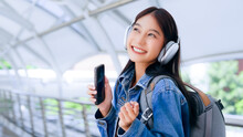 Portrait Of Happy Young Asian Woman Listening Music Online With Wireless Headphones From A Smartphone In The City
