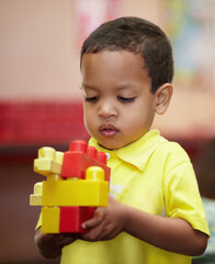 Boy, education and building blocks in classroom for thinking, scholarship or development at kindergarten. Preschool student, kid and plastic toys for play, idea or learning problem solving at academy