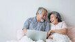 senior couple happy love Elderly couple smile face, old man and senior woman relaxing in bed room playing a laptop computer in the morning  - lifestyle senior concept