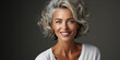 Portrait of a beautiful happy woman with gray hair, a beautiful smile, healthy facial skin in a white shirt on a gray background. Concept of facial skin care, plastic surgery, healthy eating.