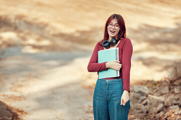 Wall Mural - Joyfully surprised student girl stands holding notebooks in her hands. Successful passing of exams.