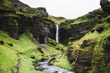 View Of A Waterfall Flowing In A Small Canyon With River In Iceland.