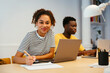 © Westend61 - Smiling student with friend using laptop in background