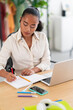 © Studio Marmellata - Young female manager in white shirt sitting at table with laptop and writing something on notebook working in light contemporary office