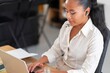 © Studio Marmellata - Serious female manager in white shirt sitting at table with laptop and looking at screen in light contemporary office