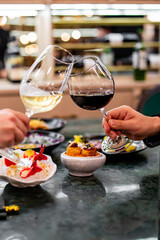 Close up of hands young couple man and woman clinking with glasses of red and white wine at restaurant