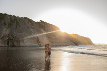 Pregnant couple kissing in sea in evening
