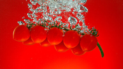 Fototapete - Freeze motion of falling fresh cherry tomatoes into water