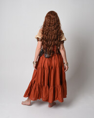 Sticker - Full length portrait of beautiful red haired woman wearing a medieval maiden, fortune teller costume. Standing pose back view, walking away. isolated on studio background.