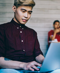 Wall Mural - Serious Asian man browsing laptop in workspace