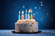 © VolumeThings - Rainbow icing colorful sprinkles lit candles on a blue background for a birthday cake