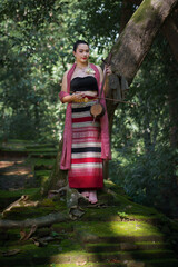 Beautiful Asian women wearing an ancient Local Thai Lanna Traditional dress costume in the old temple are happy with green natural moss in the local country of Chiang Mai, Thailand.