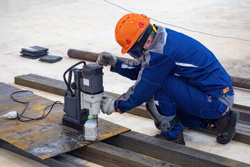 Poster - factory worker with drilling machine. man in protective helmet works with metal. manufactory worker 