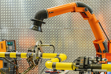 Poster - Industrial robot. Production welding equipment. Industrial robot near yellow pipe. High-tech production. Industrial robot near metal wall. Robotization of manufactory. Innovative welding equipment