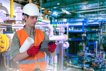 Wall Mural - Man technologist inside factory. Engineer with tablet in boiler room. Chemical factory employee. Technologist with tablet computer. Man works at chemical plant. Engineer in reflective vest