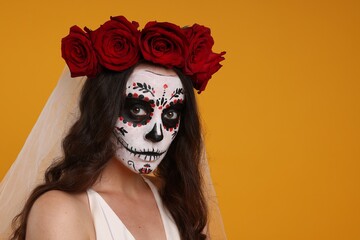 Wall Mural - Young woman in scary bride costume with sugar skull makeup and flower crown on orange background, space for text. Halloween celebration