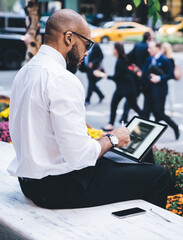 Wall Mural - Ethnic man using tablet on street bench