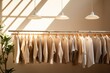 Clothes on minimal shop, shelf on cream background. Collection of clothes hanging on a rack in neutral beige colors, clean lines.