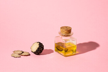 Black truffle oil on a pink background. Method for preserving truffles, aromatic oil. Season of black truffle. Autumn gourmet cuisine of Piedmont, Italy, Spain and France