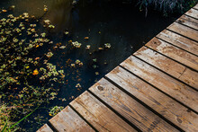 A Wooden Walkway Leads Over A Creek And Into The Woods