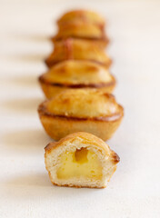 Wall Mural - Pasticciotto leccese pastries filled with egg custard cream on a white table in a line, close up