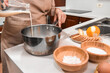 © AlbertoRodriguez - Woman's hand pouring milk into a saucepan to make custard