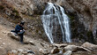 © Chepko Danil - young man with backpack sitting near the mountain river waterfall