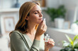 © nenetus - Beautiful woman girl holding a bottle of essential oil while testing it sitting on a couch at home.