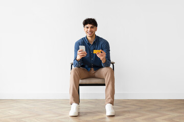 Poster - Arab guy shopping with phone and credit card sitting indoor