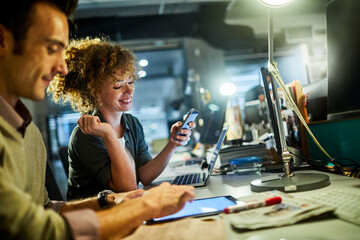 Wall Mural - Young woman using a smartphone during a group project in the office