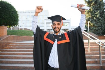 Wall Mural - Handsome indian graduate in graduation glow with diploma.