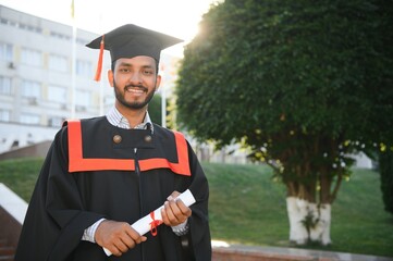 Wall Mural - Handsome indian graduate in graduation glow with diploma.