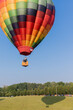 A colorful hot air balloon taking off with visible shadow.