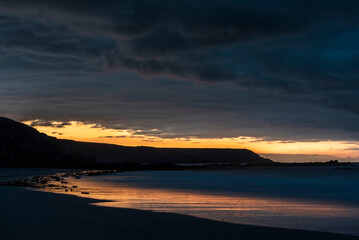 Canvas Print - Beautiful sunrise landscape image of Kennack Sands in Cornwall UK wuth dramatic moody clouds and vibrant sunburst